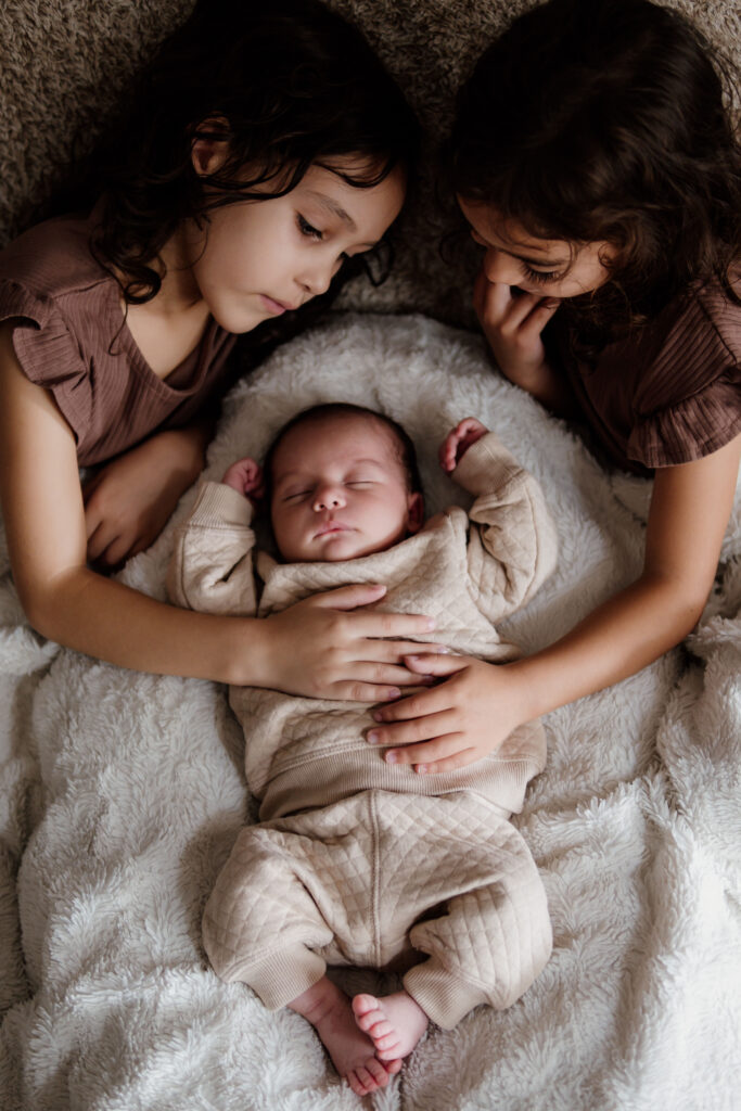 Photo d'un nouveau n&eacute; avec ses soeurs lors d'une S&eacute;ance naissance &agrave; Plan d'Orgon dans les bouches du rhone r&eacute;alis&eacute;e par No&eacute;lyne Di Muzio Photographie